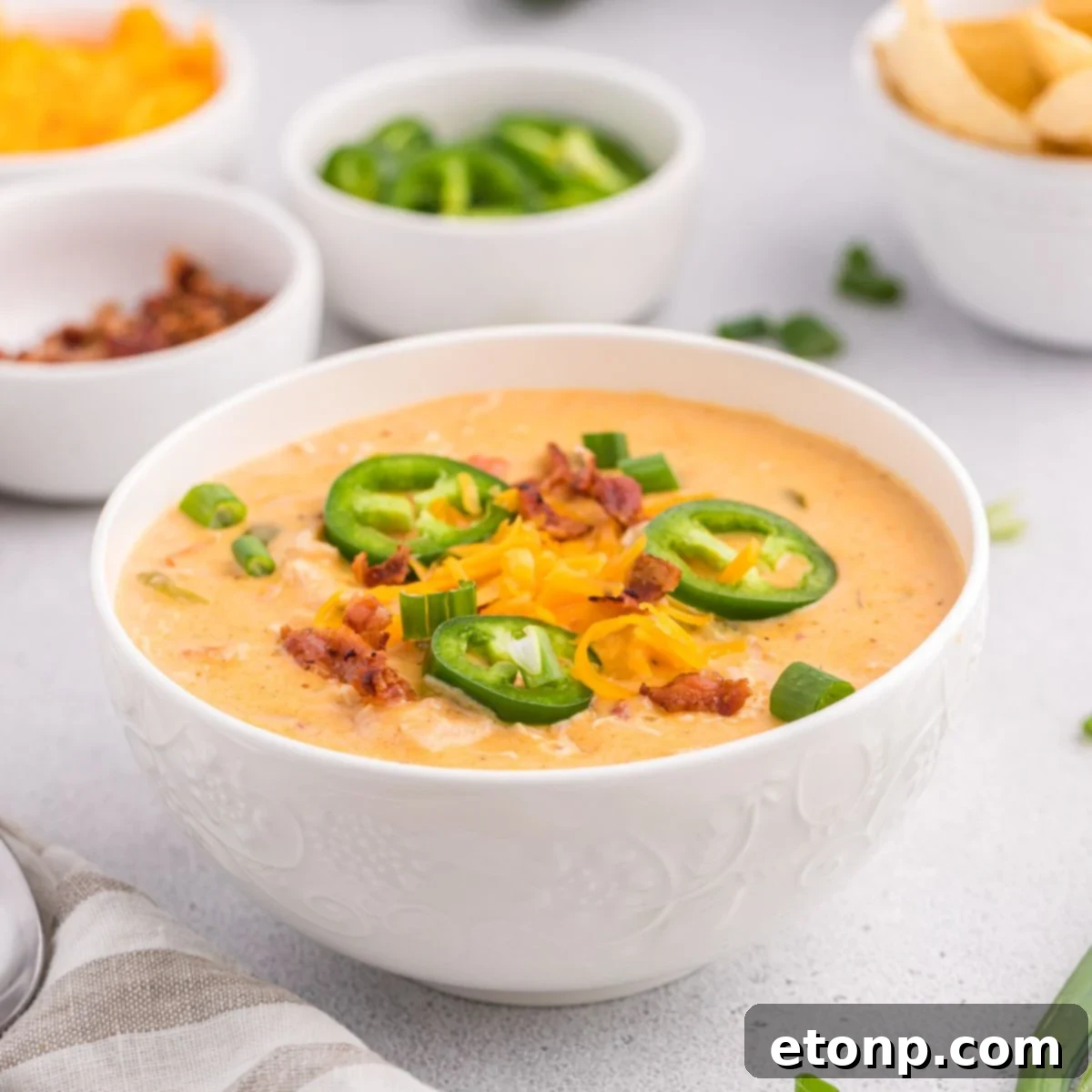 White bowls of jalapeño popper crack chicken soup with jalapeños around the soup