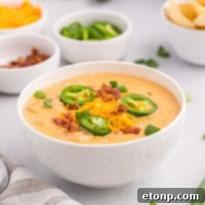 White bowls of jalapeño popper crack chicken soup with jalapeños around the soup