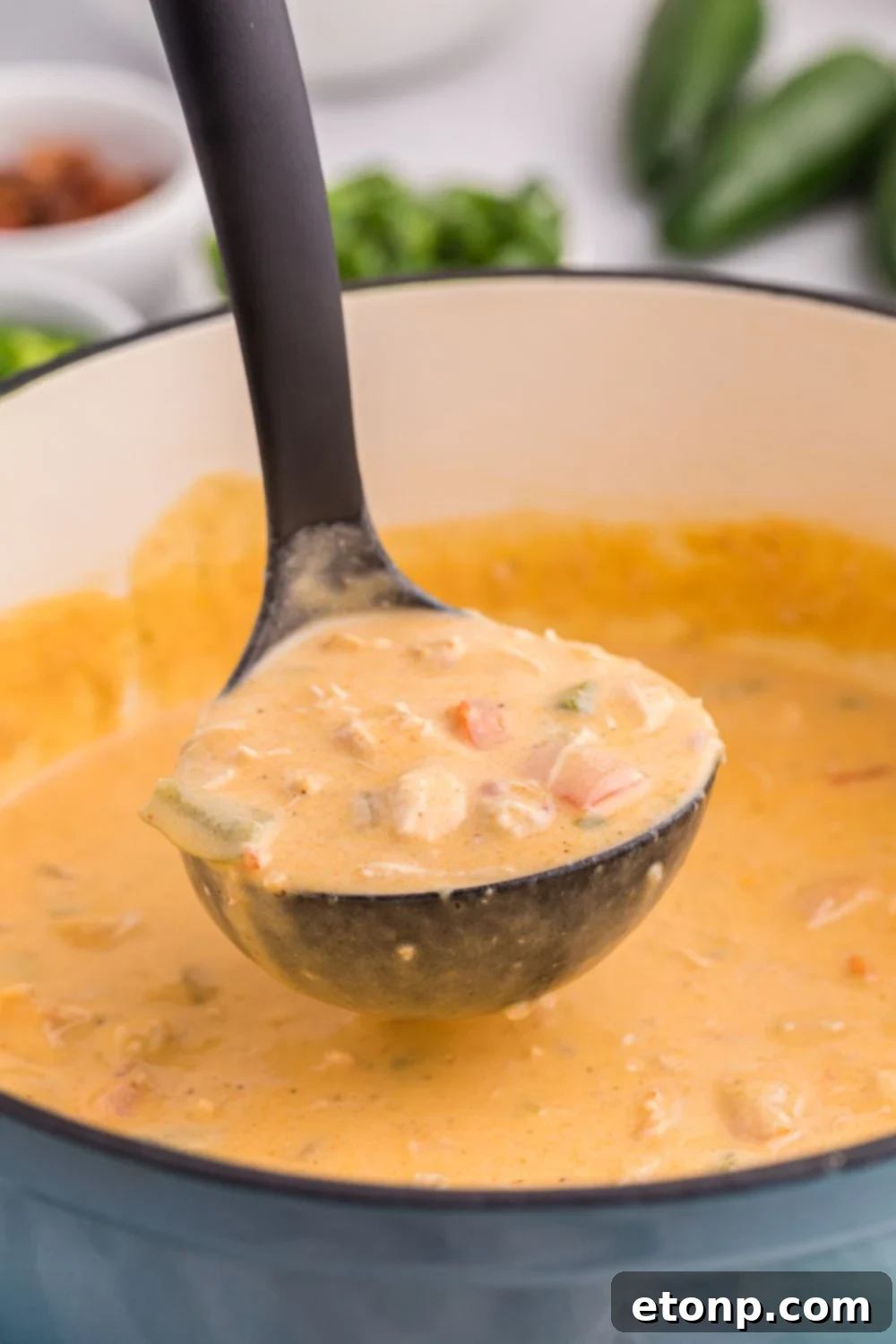 Stockpot with jalapeño popper crack chicken soup with a ladle scooping up some of the the soup