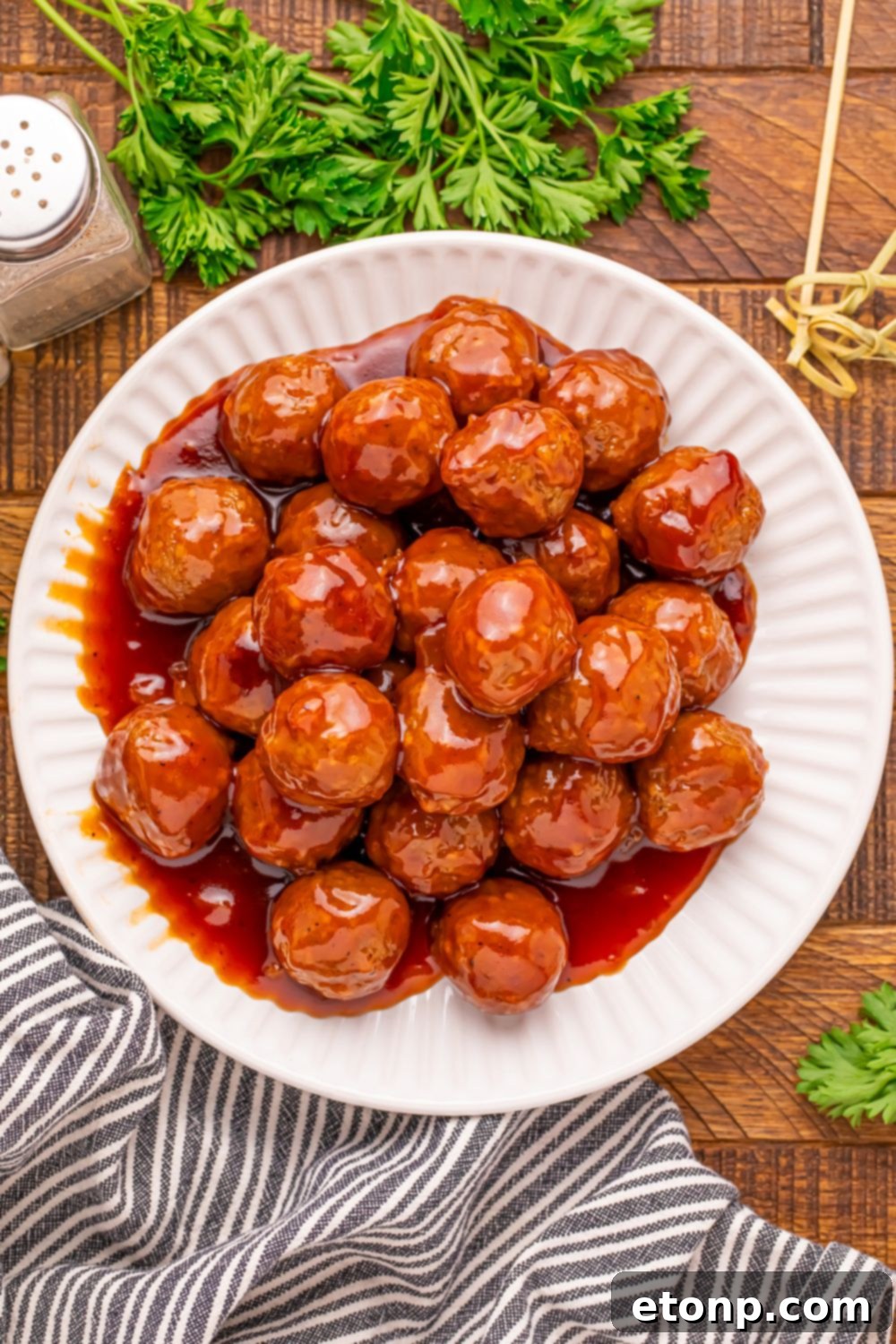 A plate of Peach BBQ Meatballs with toothpicks and parsley, ready to eat.