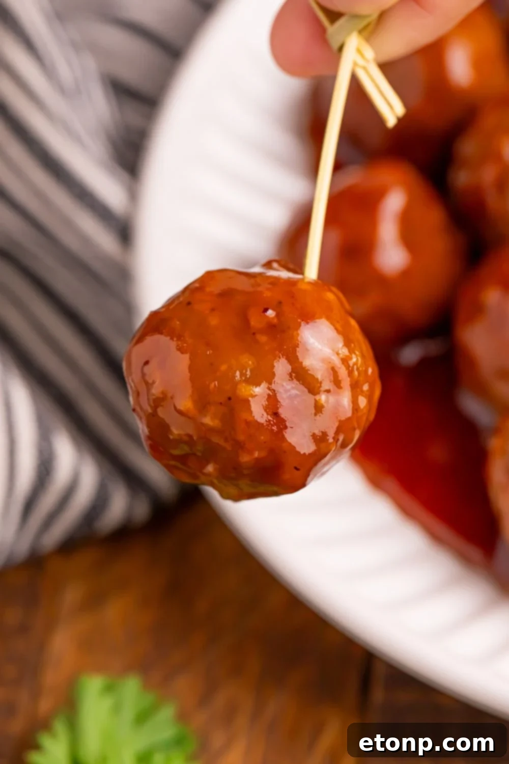 A close-up shot of a Peach BBQ Meatball on a toothpick.