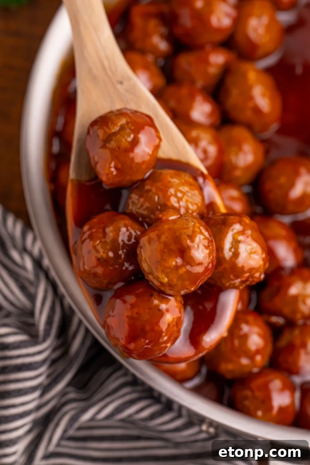 Peach BBQ Meatballs on a wooden spoon in a skillet, ready to serve.