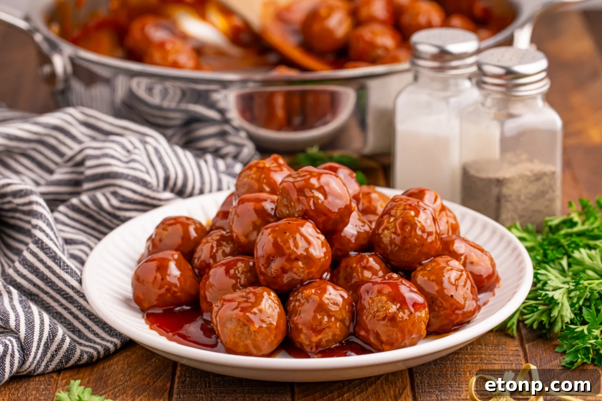 A plate of Peach BBQ Meatballs with a skillet in the background, showcasing the delicious glaze.