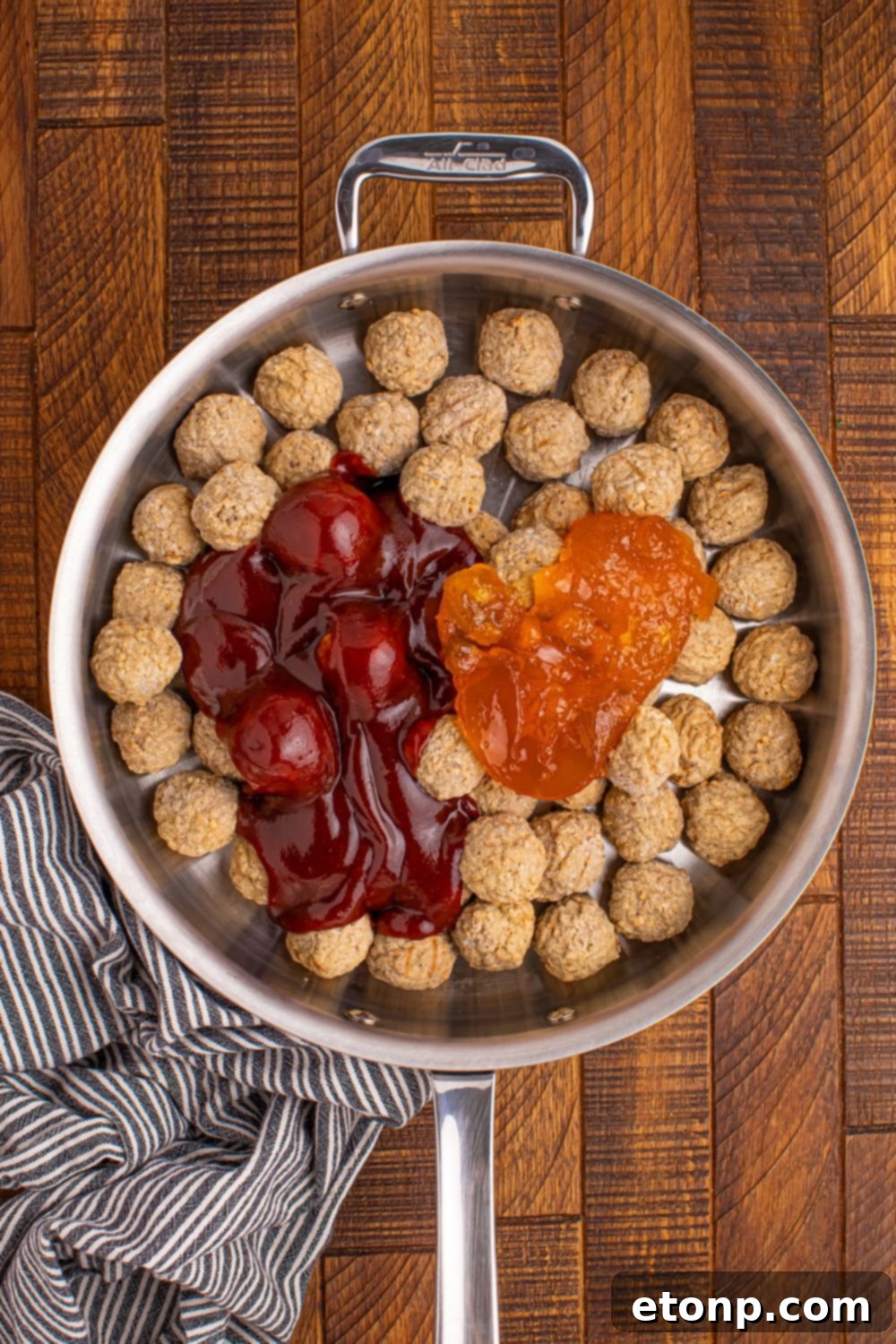 Frozen meatballs in a skillet with barbecue sauce and peach preserves, ready to cook.