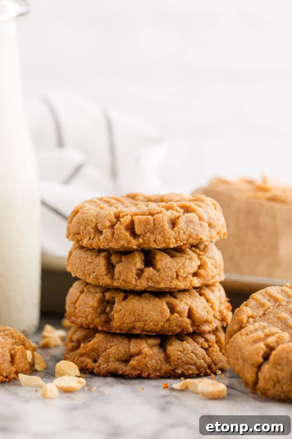 Four-Ingredient Peanut Butter Bliss: The Simplest Cookie Recipe Ever 22 Stack of peanut butter cookies with nuts and milk