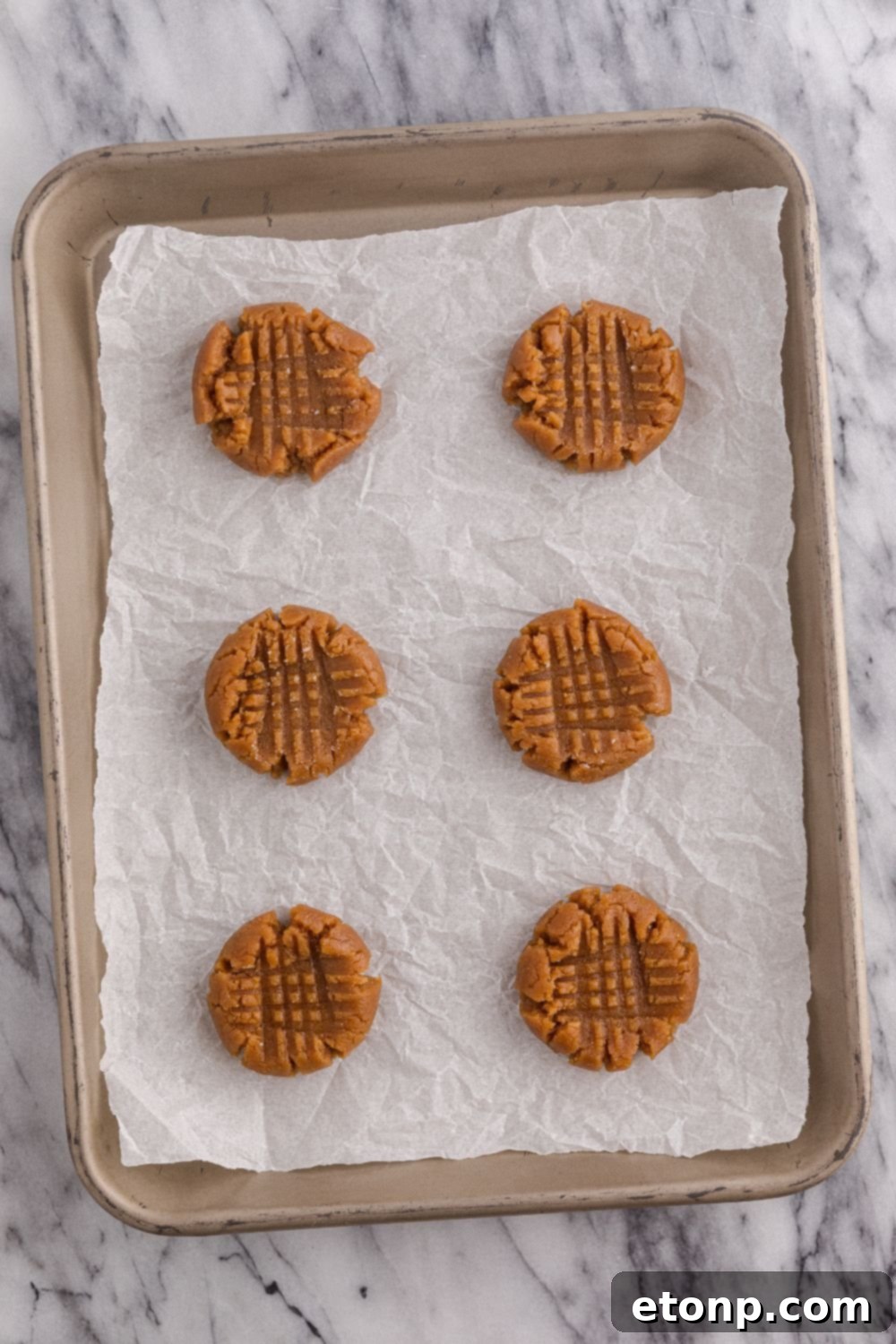 Four-Ingredient Peanut Butter Bliss: The Simplest Cookie Recipe Ever 8 Raw peanut butter cookies on a cookie sheet tray