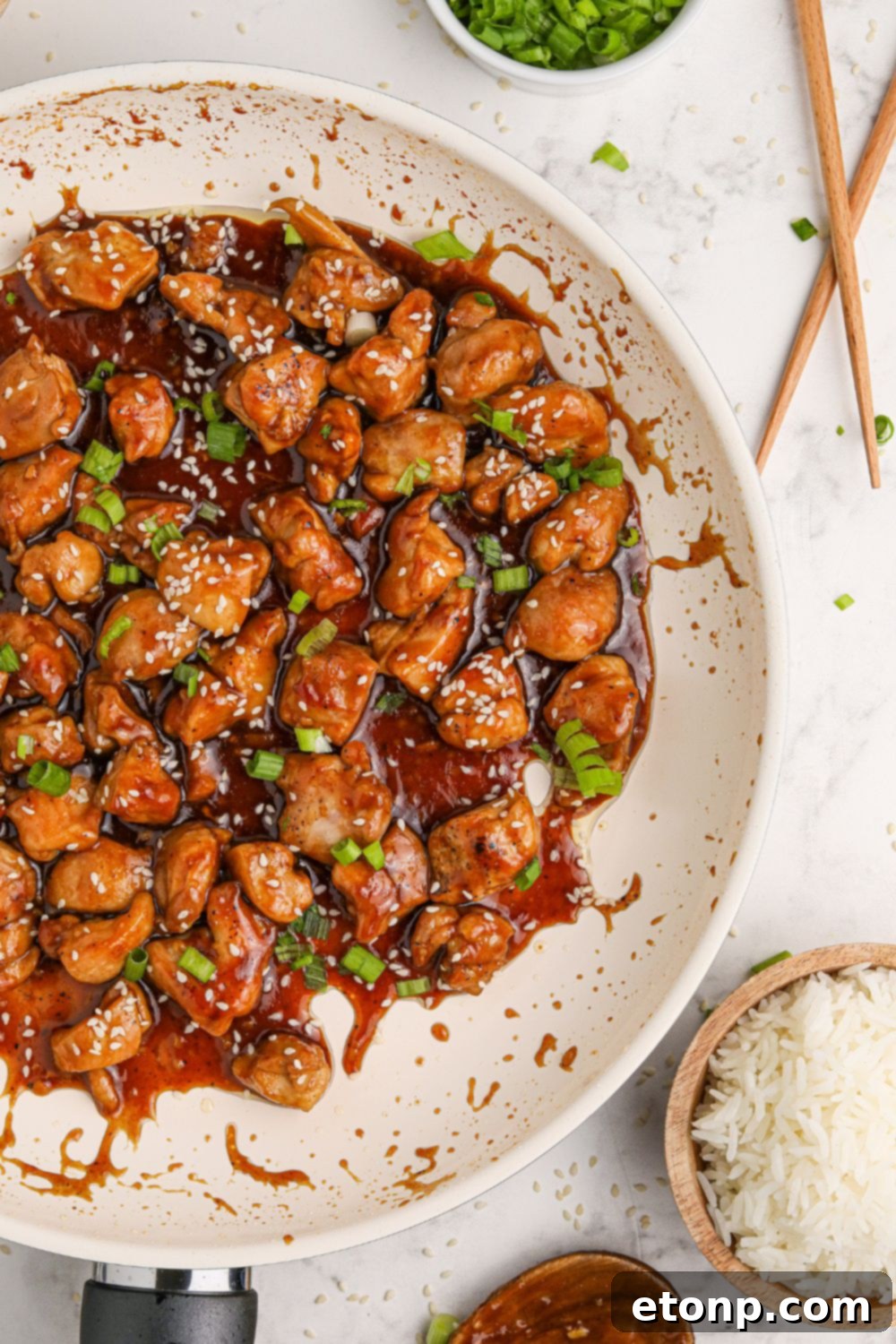 Bourbon Chicken in a skillet with chopsticks and rice