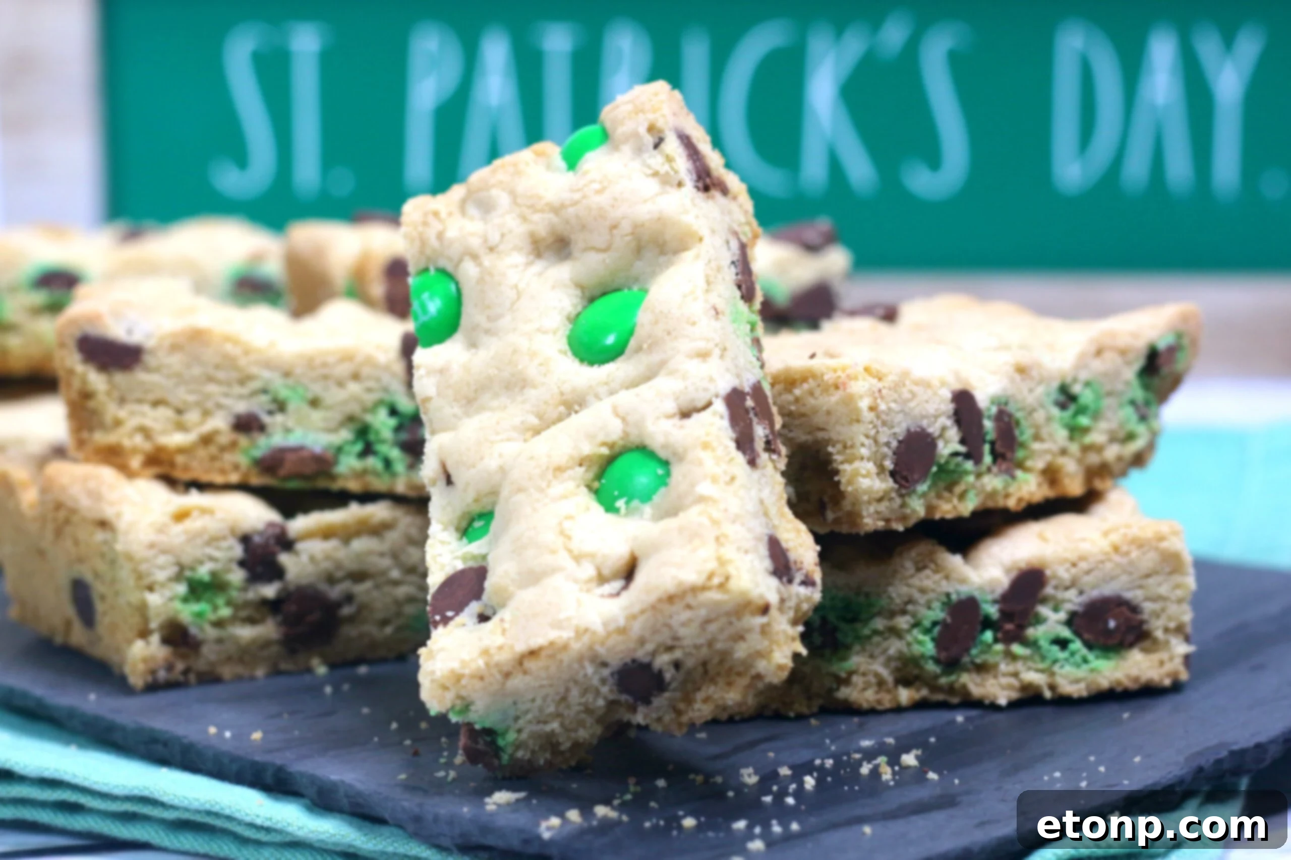 St. Patrick's Day Lucky Charm Cookie Bars 3 Saint Patrick's Day Chocolate Chip Cookie Bars on a black serving tray with st paddys day decor