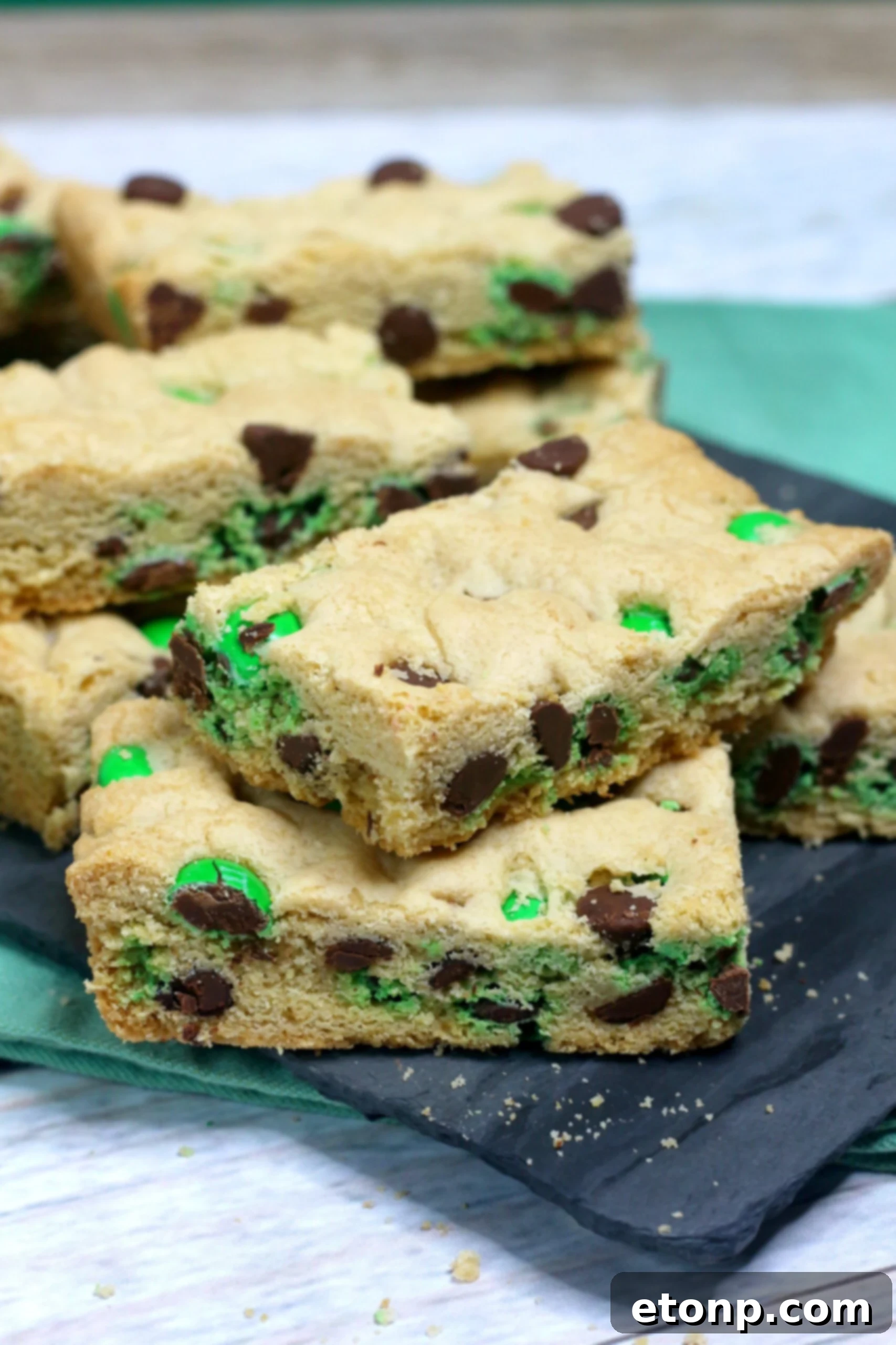 St. Patrick's Day Lucky Charm Cookie Bars 4 up close image of Saint Patrick's Day Chocolate Chip Cookie Bars on a black serving tray with st paddys day decor
