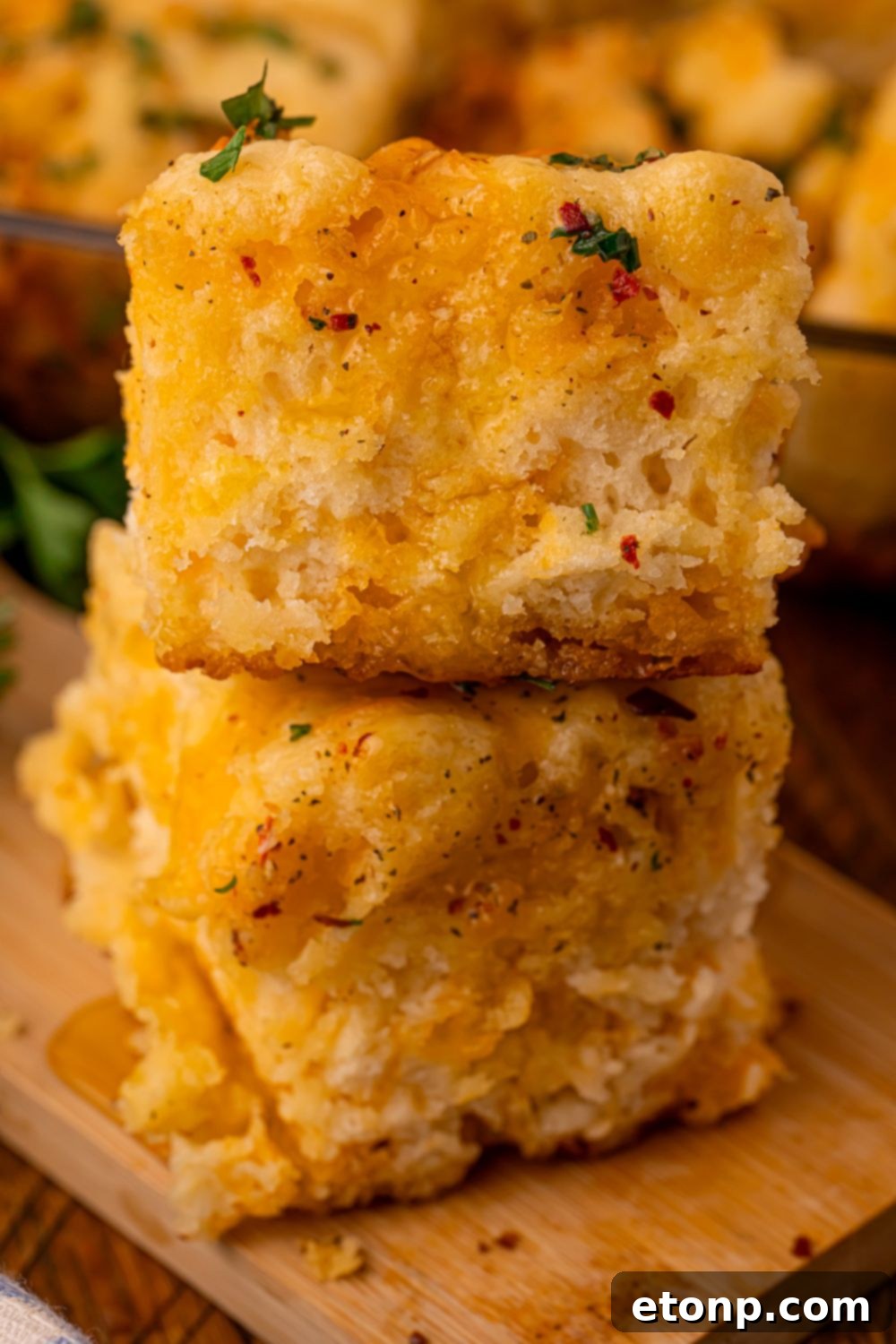 Effortless Butter Drenched Cowboy Biscuits 12 A stack of Cowboy Butter Swim Biscuits on a table with more biscuits in the pan behind them.