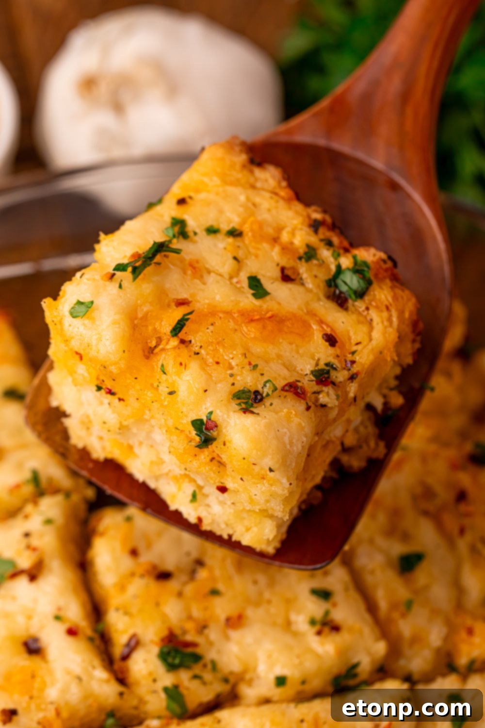 Effortless Butter Drenched Cowboy Biscuits 10 A wooden spoon lifting a fluffy biscuit out of the baking pan.