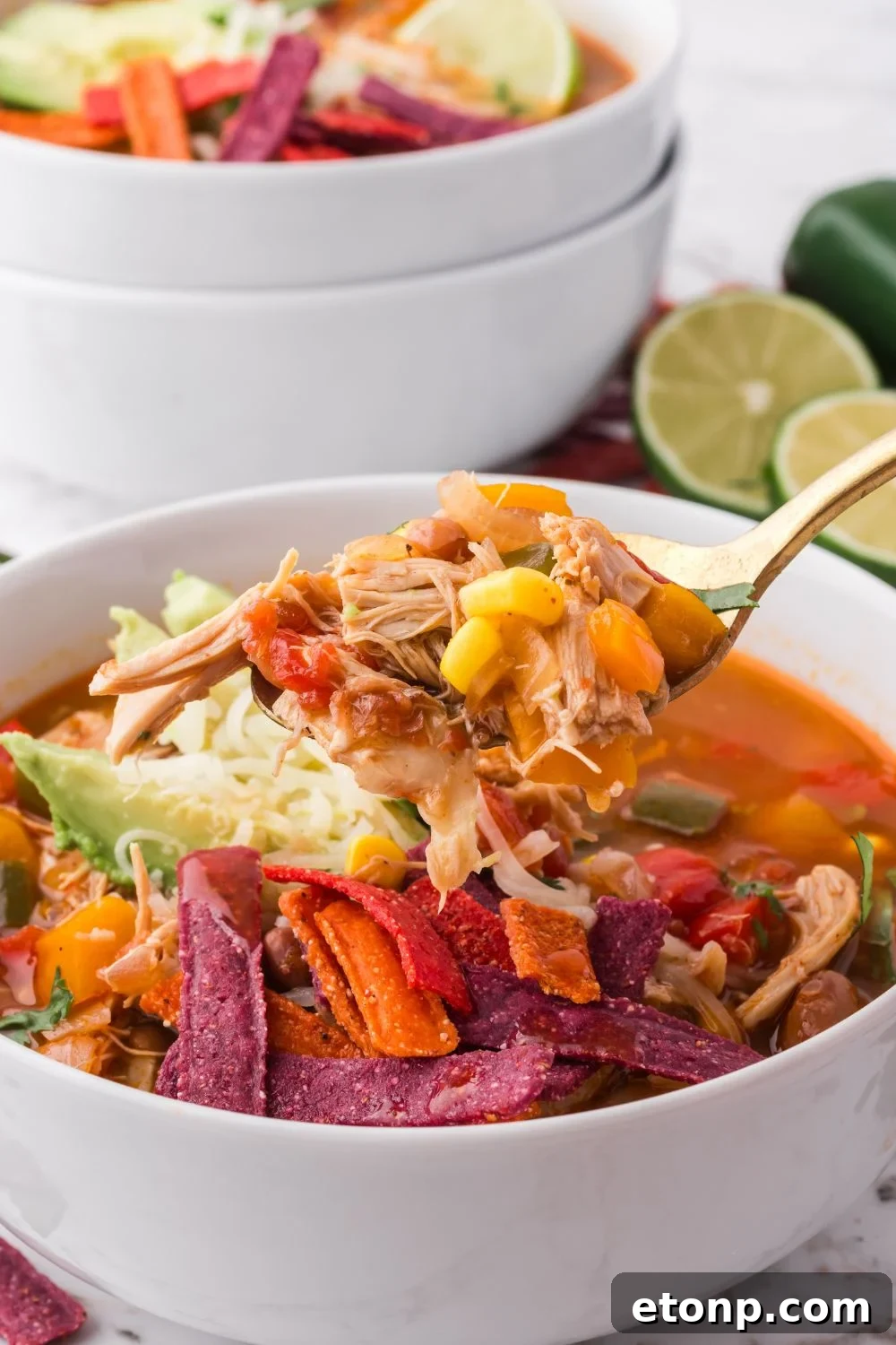 spoon lifting up some of the Southwestern Chicken Soup in a white bowl on the table 