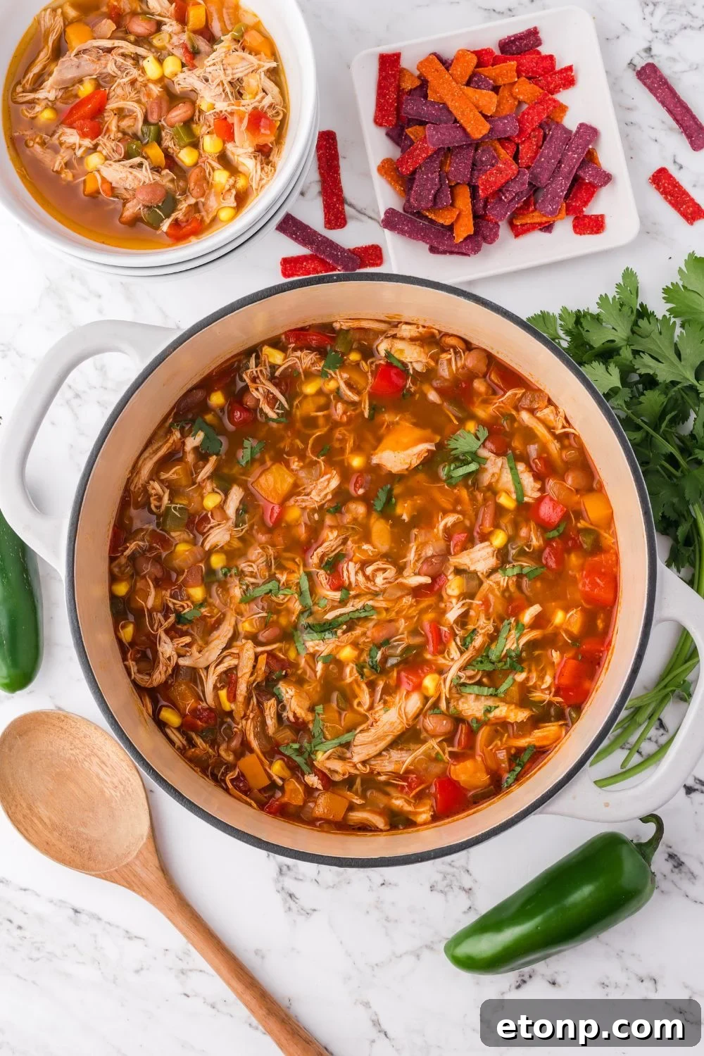 a white pot on table with southwestern soup in a pot and another small bowl to the side and chips to the side 